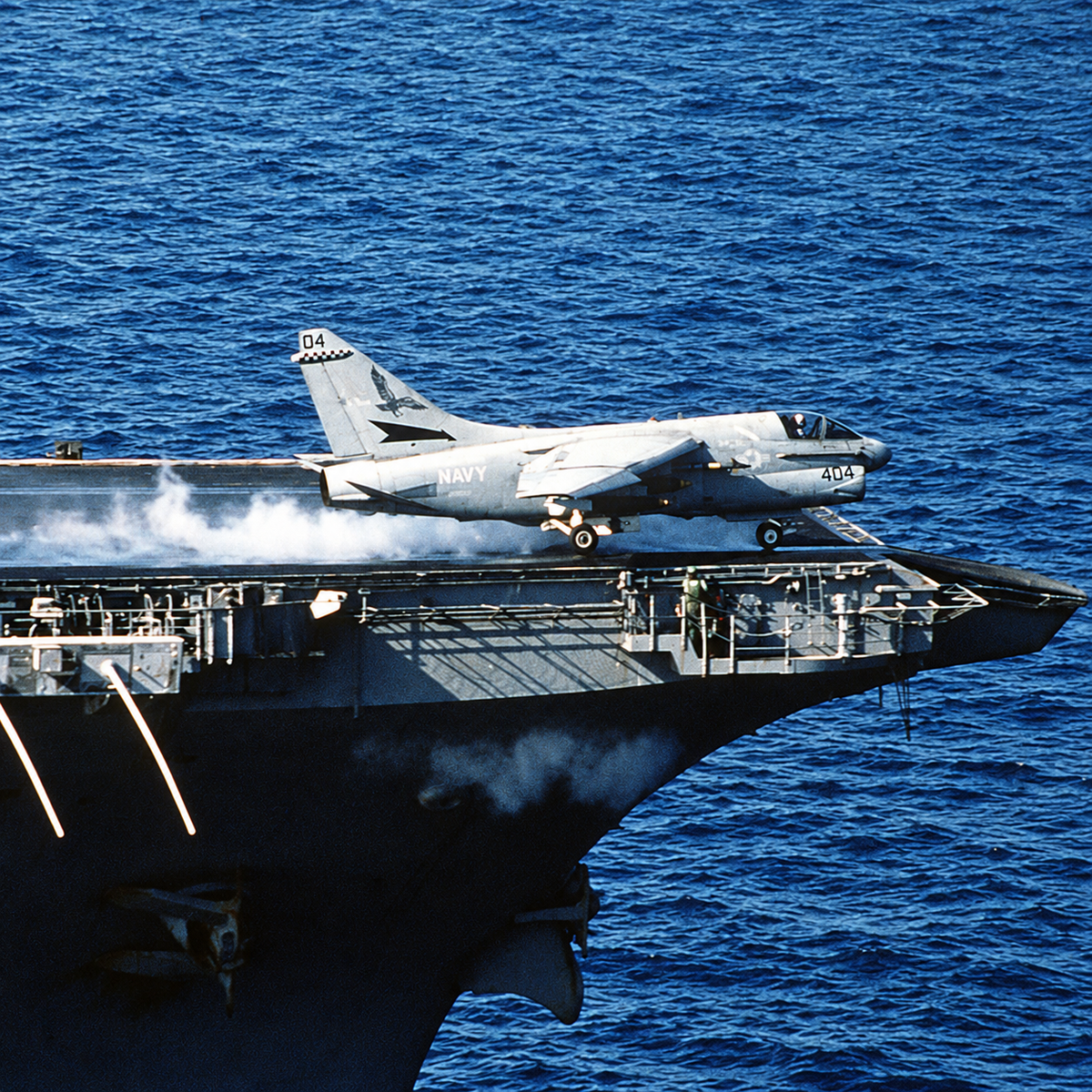 A VA-72 A-7E Corsair II marked “404” launches from an aircraft carrier with the sea behind it.