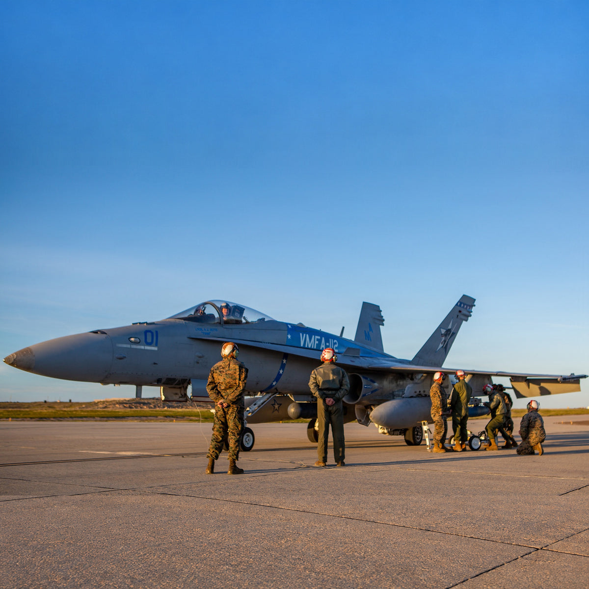 Marines conduct hot-loading training beside a VMFA-112 F/A-18C Hornet marked 01 on the tarmac.